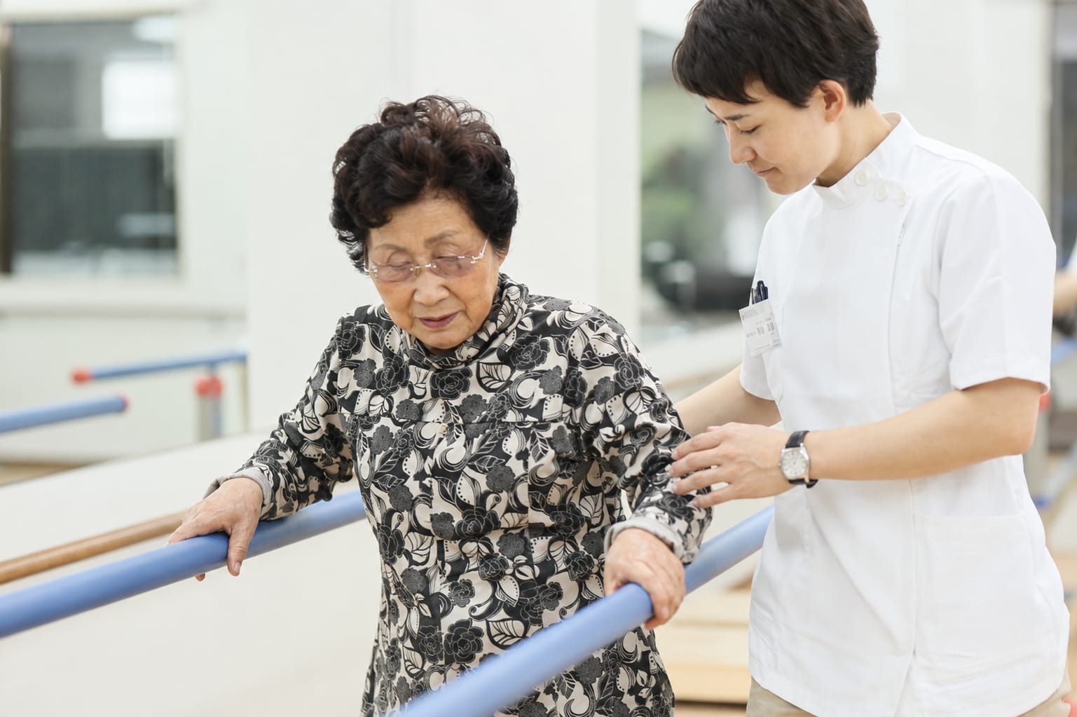 平行棒を使った歩行訓練をスタッフが見守る様子