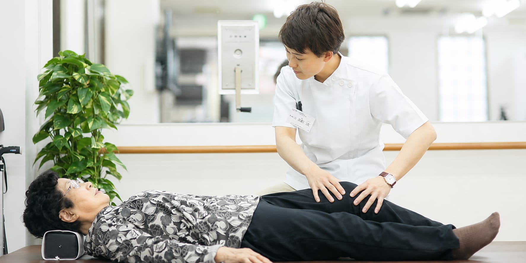 専門職がご利用者様の脚に触れて個別に機能訓練を行う様子